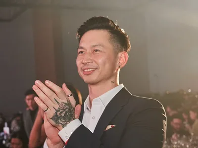 Roger Wong smiling and applauding at an evening event